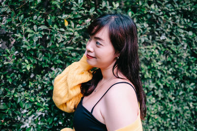 Close up of young pretty asian woman in blue yellow sweater with garden background.