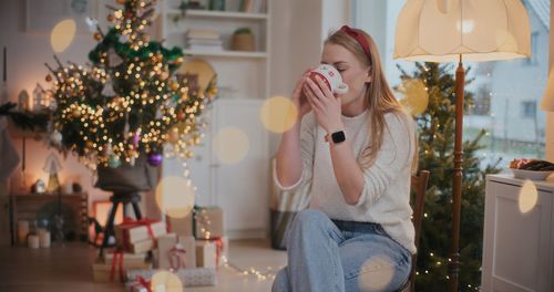 Young woman holding christmas tree at home