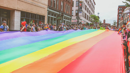 People holding rainbow flag in city