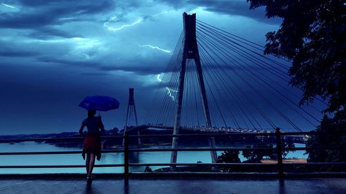 Man on bridge against sky during sunset