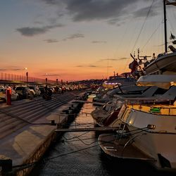 Sailboats moored at harbor during sunset