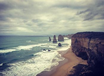 Scenic view of beach against cloudy sky