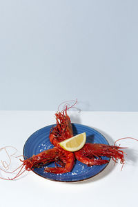 Tasty seafood of cooked red shrimps with fresh lemon slices and coarse salt on white background