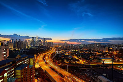 High angle view of illuminated cityscape against blue sky