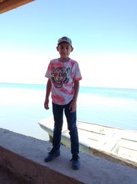 Portrait of boy standing in sea against sky