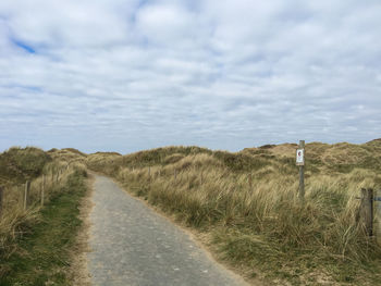 Road amidst field against sky