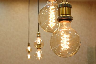 Close-up of light bulb hanging against wall