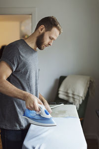 Side view of man ironing shirt