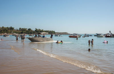 People on beach against clear sky