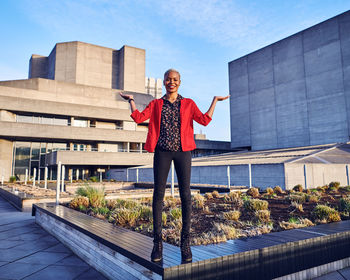 Portrait of young woman standing against built structure