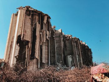 Low angle view of damaged building against clear blue sky