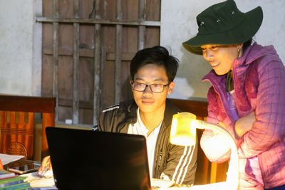 Vietnamese young man helping mother using a laptop in the kitchen