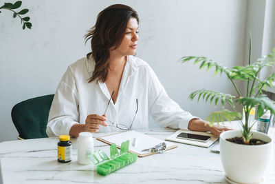 Young brunette woman nutritionist plus size in white shirt working at laptop in bright modern office