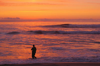 Silhouette of amateur fisherman in the sunset, sport fishing, recreational fishing on the beach