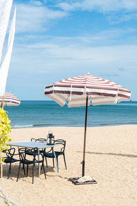 Deck chairs on beach against sky