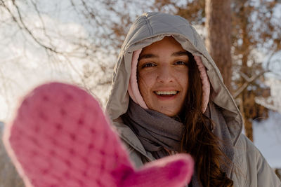 Woman with freckles in winter clothes with mittens outdoors enjoys winter