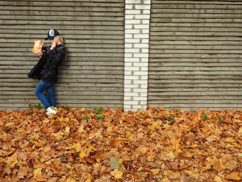Man standing by autumn leaves