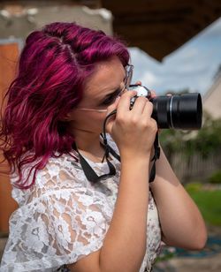 Side view of woman photographing with camera