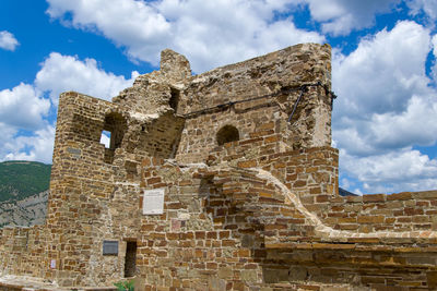 Low angle view of old building against cloudy sky