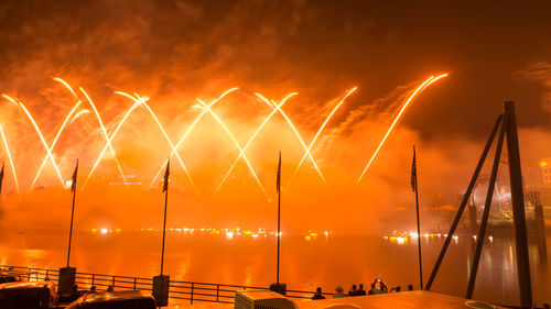 Firework display over sea against sky at night