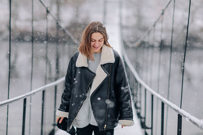 Young woman standing against railing