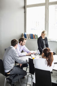 Mid adult businessman discussing over photograph with colleagues at desk in office