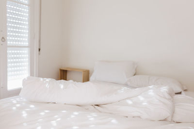 White bedding sheets and pillow in apartment at morning time with sunlight from windows