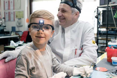 Portrait of boy sitting with worker in workshop