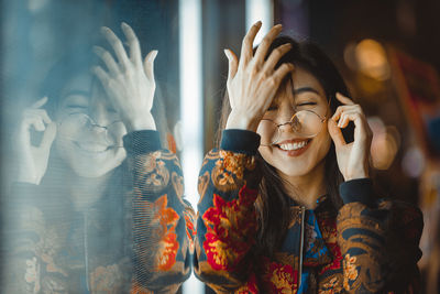 Smiling young woman by window with reflection