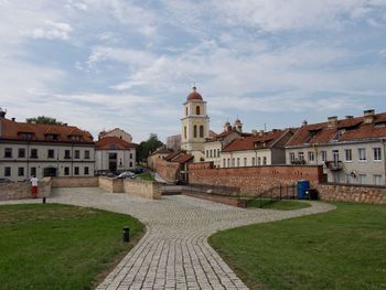 Footpath amidst buildings in city against sky