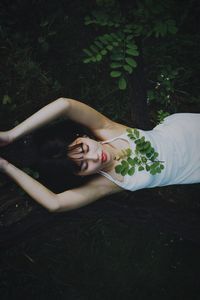 Portrait of young woman lying on plant