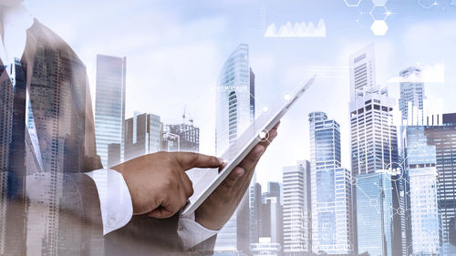 Double exposure of businessman using digital tablet and cityscape