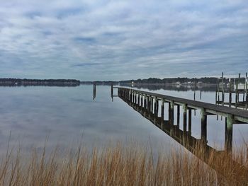 Pier on lake against cloudy sky