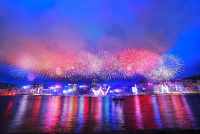 Firework display over river against sky at night