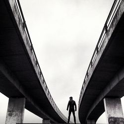 Low angle view of woman standing on bridge against sky