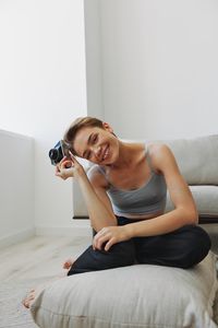 Young woman using mobile phone while lying on sofa at home