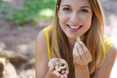 Close-up of healthy brazilian woman picking brazil nuts from her hand outdoors. looks at camera.