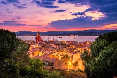 High angle view of illuminated building by sea against sky during sunset