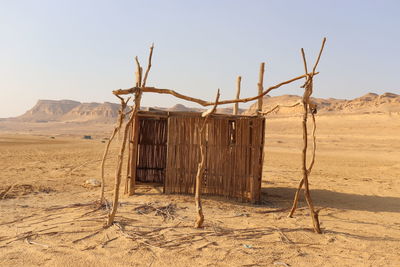 Wooden posts on desert against clear sky