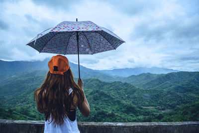 Rear view of woman standing on mountain against sky