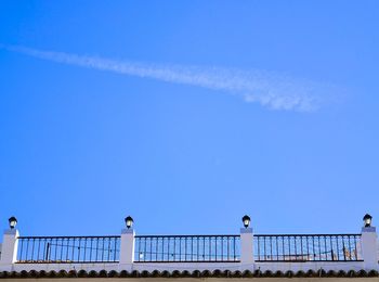 Low angle view of seagull perching on railing against blue sky