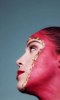 Close-up portrait of a young woman looking away against gray background