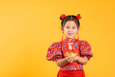 Portrait of girl standing against yellow background