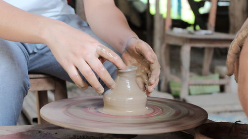 Midsection of people working on pottery wheel at workshop