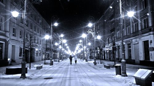 People walking on illuminated street at night in winter