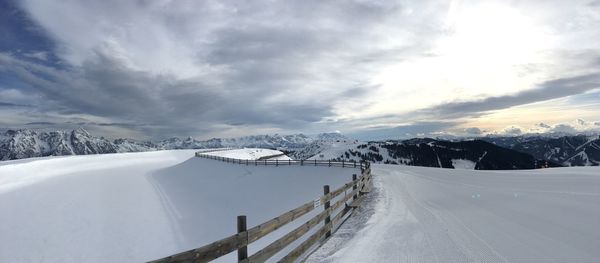 Snow covered mountain road against cloudy sky