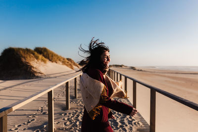 Woman looking away while standing on railing against clear sky