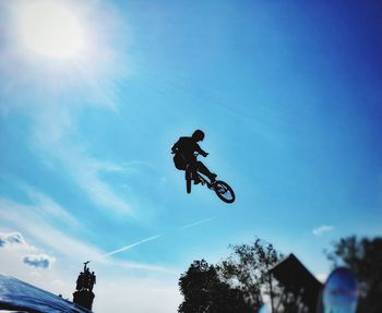 Low angle view of man jumping against sky