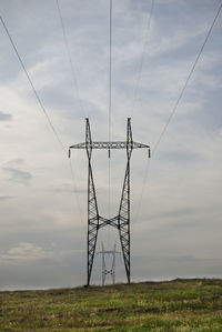 Low angle view of electricity pylon on field against sky