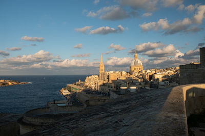 Panoramic view of buildings and sea against cloudy sky